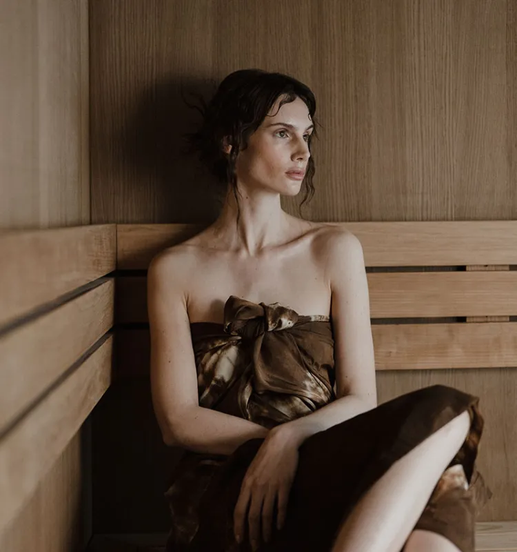 Frau entspannt in der Sauna des Grand Elisabeth, umgeben von warmem Holz und ruhiger Atmosphäre im Wellnessurlaub in Bad Ischl.