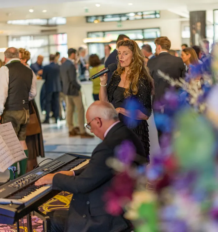 Sängerin und Pianist bei einer Abendveranstaltung im Grand Elisabeth Bad Ischl mit festlich gekleideten Gästen im Hintergrund