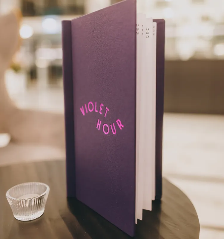 Die stilvolle Cocktailkarte der Hotelbar Violet Hour mit geprägtem Logo in Pink