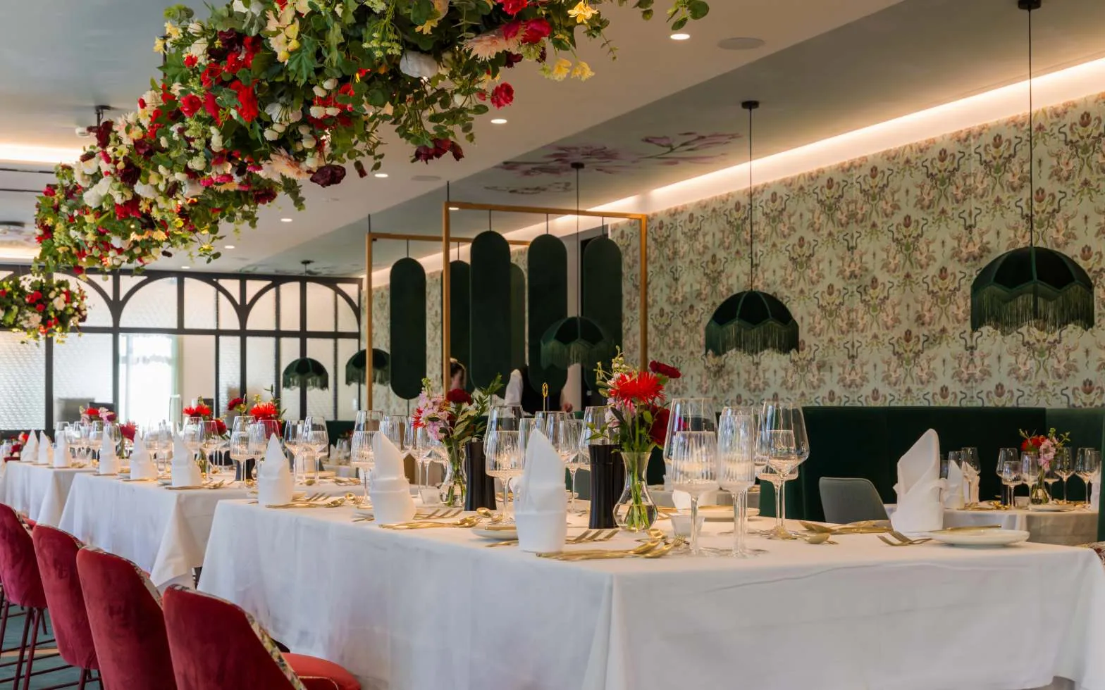 Lange festlich gedeckte Tafel mit weißen Tischdecken, roten Samtstühlen und floralem Blumenschmuck im Restaurant des Grand Elisabeth Bad Ischl