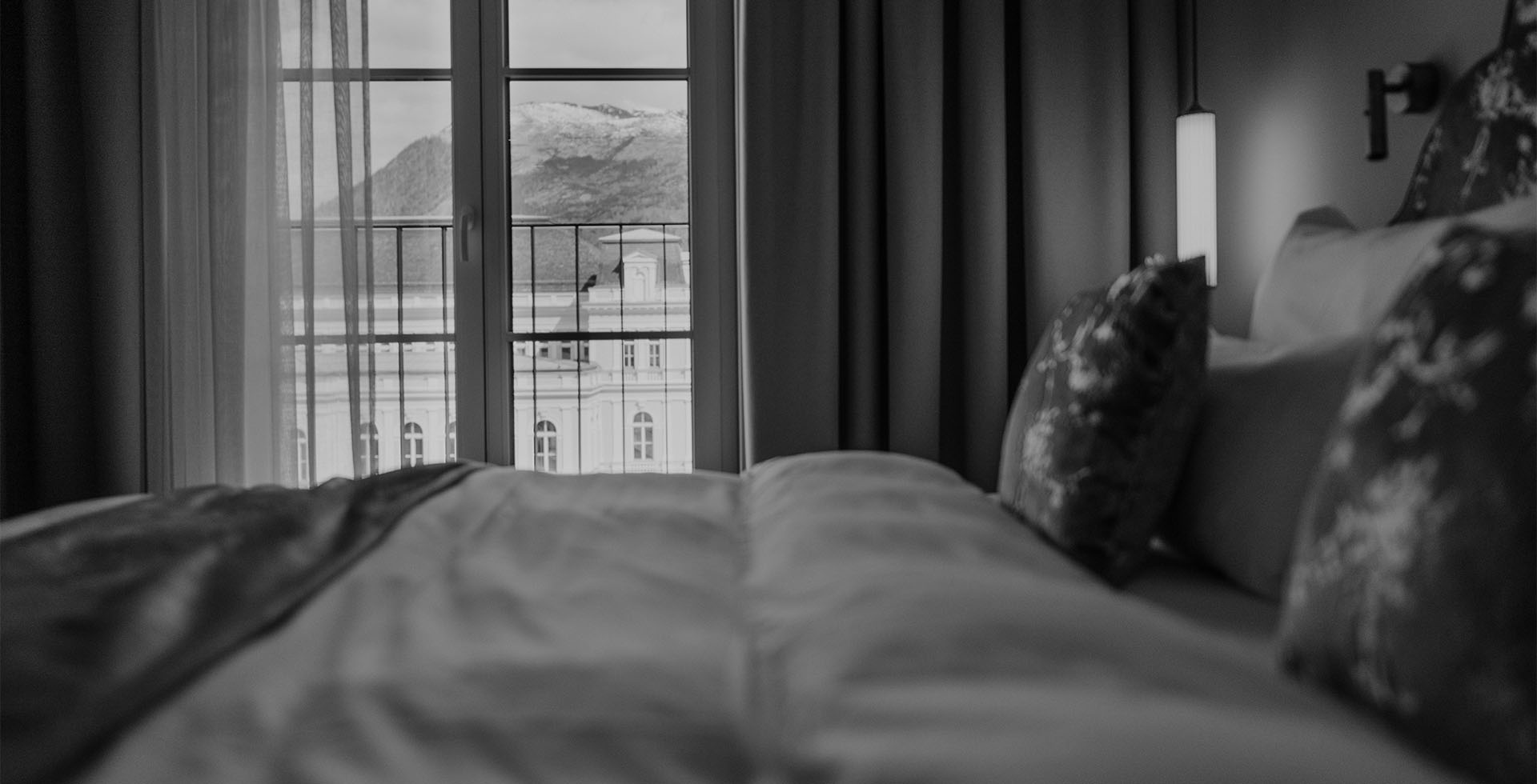 Classic Doppelzimmer mit Blick durch das Fenster auf Berge und historische Fassade im Grand Elisabeth Hotel in Bad Ischl.