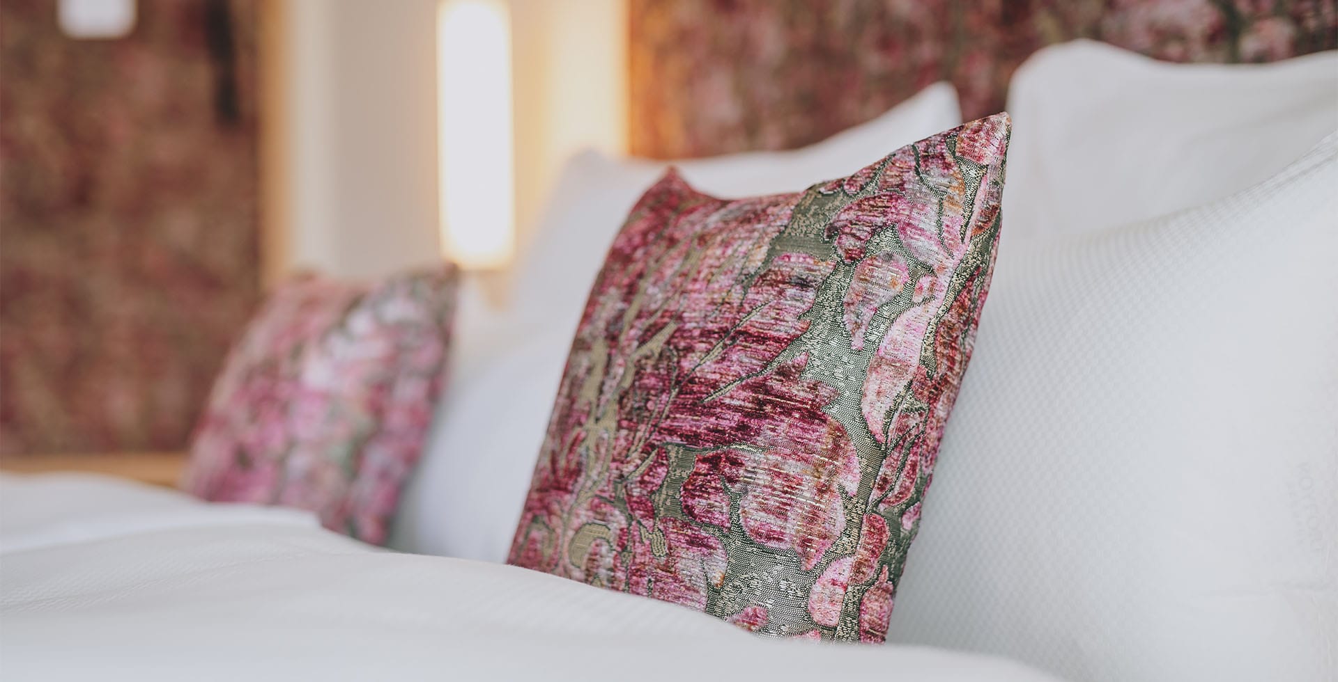 Detailaufnahme der kunstvoll gemusterten Kissen in der Sisi Suite des Grand Elisabeth, die kaiserlichen Flair ins Schlafzimmer in Bad Ischl bringen.