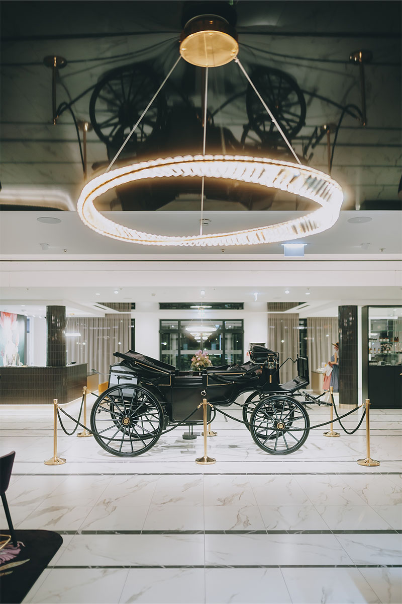 Historische Kutsche in der Lobby des Grand Elisabeth Hotels Bad Ischl mit modernem Kronleuchter